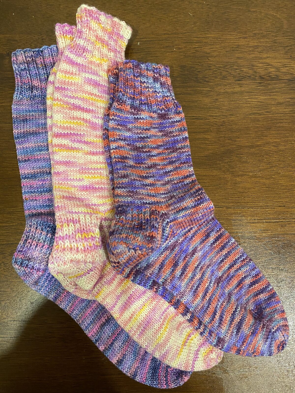 Rows of hand-knit wool socks in natural and dyed yarns, ready to be shipped